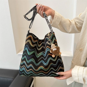 Close-up of colorful wavy knit tote bag with patterned wide strap and plush charm