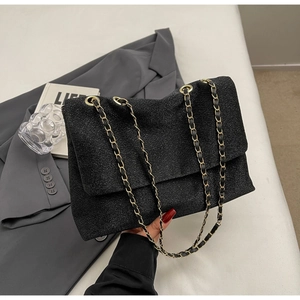 Detail of black sequined tote bag with golden chain strap and high-end texture finish
