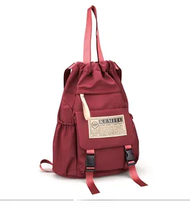 Detail view of burgundy waterproof nylon backpack with drawstring closure and dual buckles