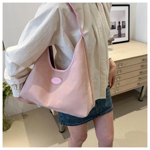 Detail view of the soft pink nylon shoulder bag featuring smooth leather edges and trim