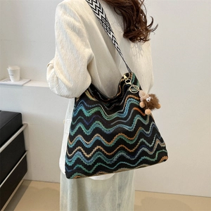 Close-up of zigzag knit tote bag with thick woven strap and plush monster charm detail