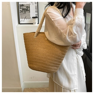 Close-up of a hand-woven straw tote bag featuring thick cotton rope handles and beige fiber