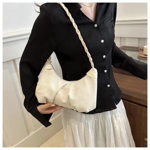 Close-up of white ruched hobo bag with braided strap worn by a model in casual style