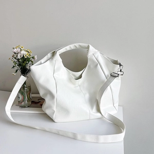 Minimalist white PU leather tote bag with pleated texture on a table with flowers