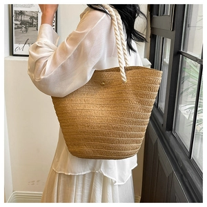 Close-up of natural woven straw tote with thick cotton rope handles and metal eyelets