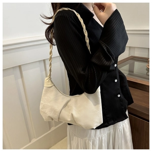 Detail shot of the cream shoulder bag showing the braided rope strap and pleated texture