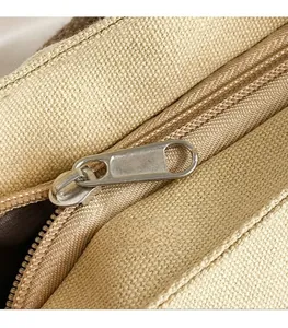 Close-up of the smooth metal zipper and coarse canvas texture on a tote bag