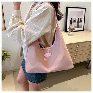 Detailed shot of pink nylon tote bag showing soft fabric texture and elegant logo plaque