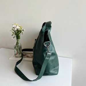 Detail view of large dark green tote bag with lychee texture and silver metal hardware