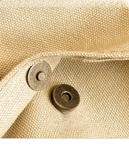 Close-up of vintage bronze magnetic snap button on textured beige canvas tote bag