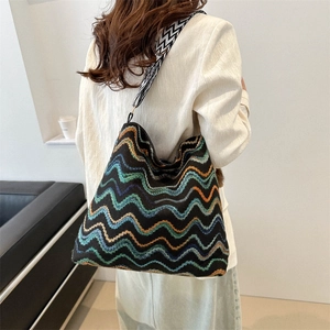 Close-up of vibrant colorful striped knit tote bag with geometric wide shoulder strap