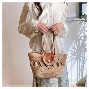 Close-up of woven tote bag featuring colorful dots, leather flap, and pearl buckle