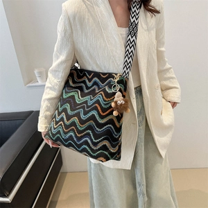 Detail of colorful wave knit velvet tote bag with geometric strap and monster charm