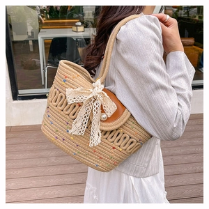 Detail of hand-woven cotton shoulder bag featuring pearl clasp and white lace bow
