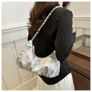 Detail of silver metallic hobo bag featuring pleated texture and braided shoulder strap