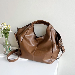 Detail of soft brown PU leather hobo bag with natural folds and silver metal hardware