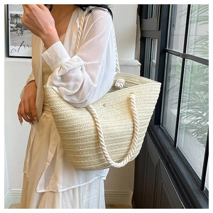 Detailed close-up of woven beige tote bag featuring thick white cotton rope handles