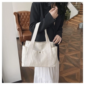 Detailed macro view of large canvas tote bag with front pocket and vintage metal buckle