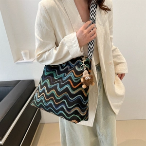 Detail of colorful zigzag stripe tote bag with wide shoulder strap and plush charm