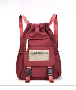 Detailed front view of the burgundy nylon backpack featuring drawstring closure and buckles