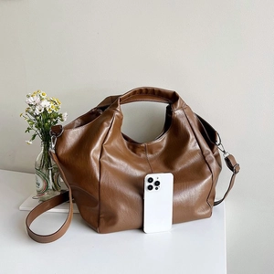 Brown leather slouchy tote bag shown with a smartphone to demonstrate large storage capacity