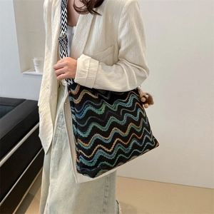 Detail of colorful striped velvet tote bag with wide geometric strap and brown pompom