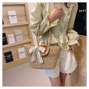 Detail of hollow woven cotton tote with brown leather handles and a lace bow accent