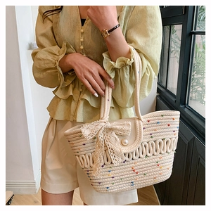 Close-up of woven cotton shoulder bag featuring a lace bow and pearl magnetic clasp
