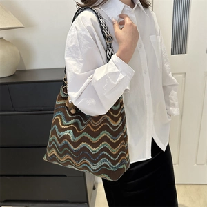 Detail of colorful wave pattern knit tote bag with decorative plush charm and wide strap