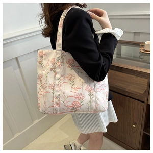 Borsa tote in tela floreale indossata a spalla per mostrare le dimensioni reali