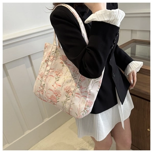 Borsa tote in tela floreale con tasca frontale indossata a spalla in una stanza moderna
