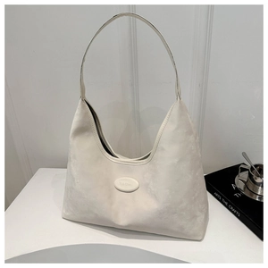 Detailed macro view of the cream-colored soft texture and brand tag on the hobo bag
