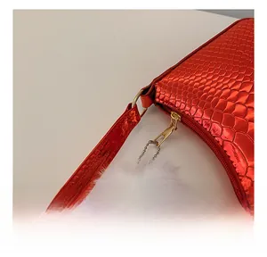 Detail of red snake pattern texture on shoulder bag with white faux fur pompom charm