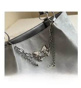 Détail d'un cabas en daim gris avec chaînes argentées et pendentif papillon élégant