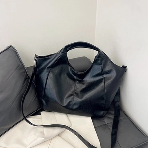Detail view of a large black faux leather Hobo bag with integrated handle and long strap
