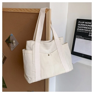 Detail of white multi-pocket canvas tote bag with metal buckle and shoulder straps