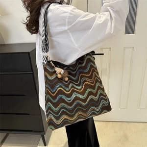 Detail of colorful striped woven velvet tote with geometric wide strap and plush pendant