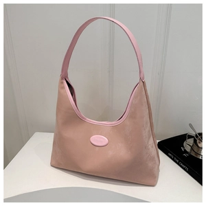 Detail shot of a soft pink suede hobo bag with an oval logo on a desktop scene