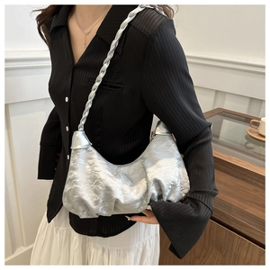 Detail of silver pleated crescent bag with braided shoulder strap on model shoulder
