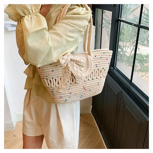 Detail of off-white woven tote bag with large lace bow and elegant pearl button closure