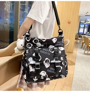 Detail view of black canvas crossbody bag with white bear prints and plush charm pendant
