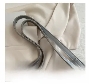 Gros plan sur la bandoulière en cuir gris et les anneaux métalliques du sac