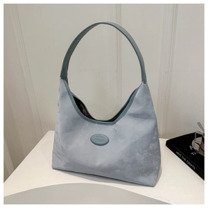 Close-up of soft light blue suede hobo bag with minimalist texture and oval brand plaque