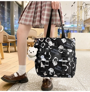 Detail of black canvas tote bag with bear print, front pocket and plush charm
