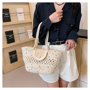 Close-up of beige woven bag with rainbow polka dots and elegant large pearl buckle detail