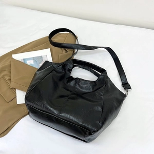 Detail view of black soft faux leather tote bag with round handles and long adjustable strap