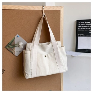 Detail of off-white canvas tote bag featuring sturdy handles and side pocket