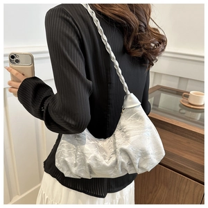 Silver metallic pleated cloud bag with braided strap shown in a lifestyle casual setting