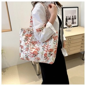 Primo piano di una borsa tote in tela bianca con stampe floreali di ortensie rosse e arancioni