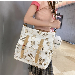 Detail of white canvas tote with cute bear print, plush charm and adjustable strap